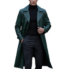 Man wearing a long green coat over a black outfit on a white background